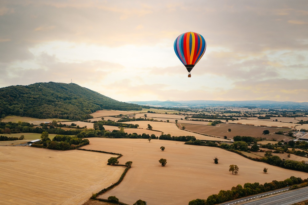 An aerial photograph showing a hot ait balloon flying over the Wrekin hill.