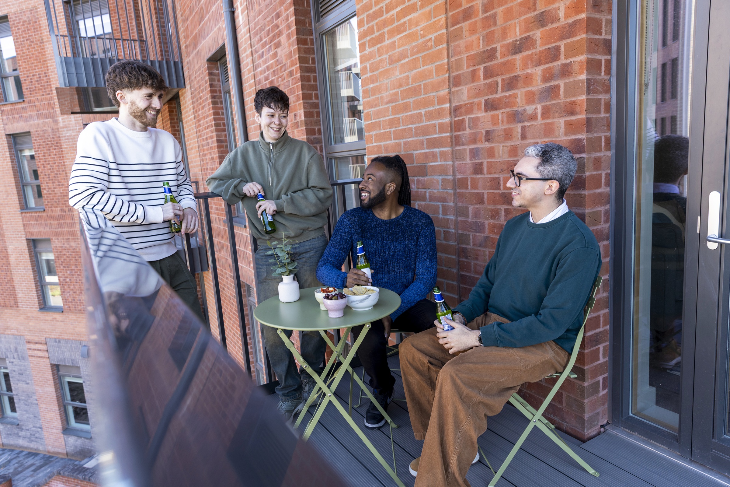 A photograph showing a group of friends enjoying a drink on the private balcony of an apartment.