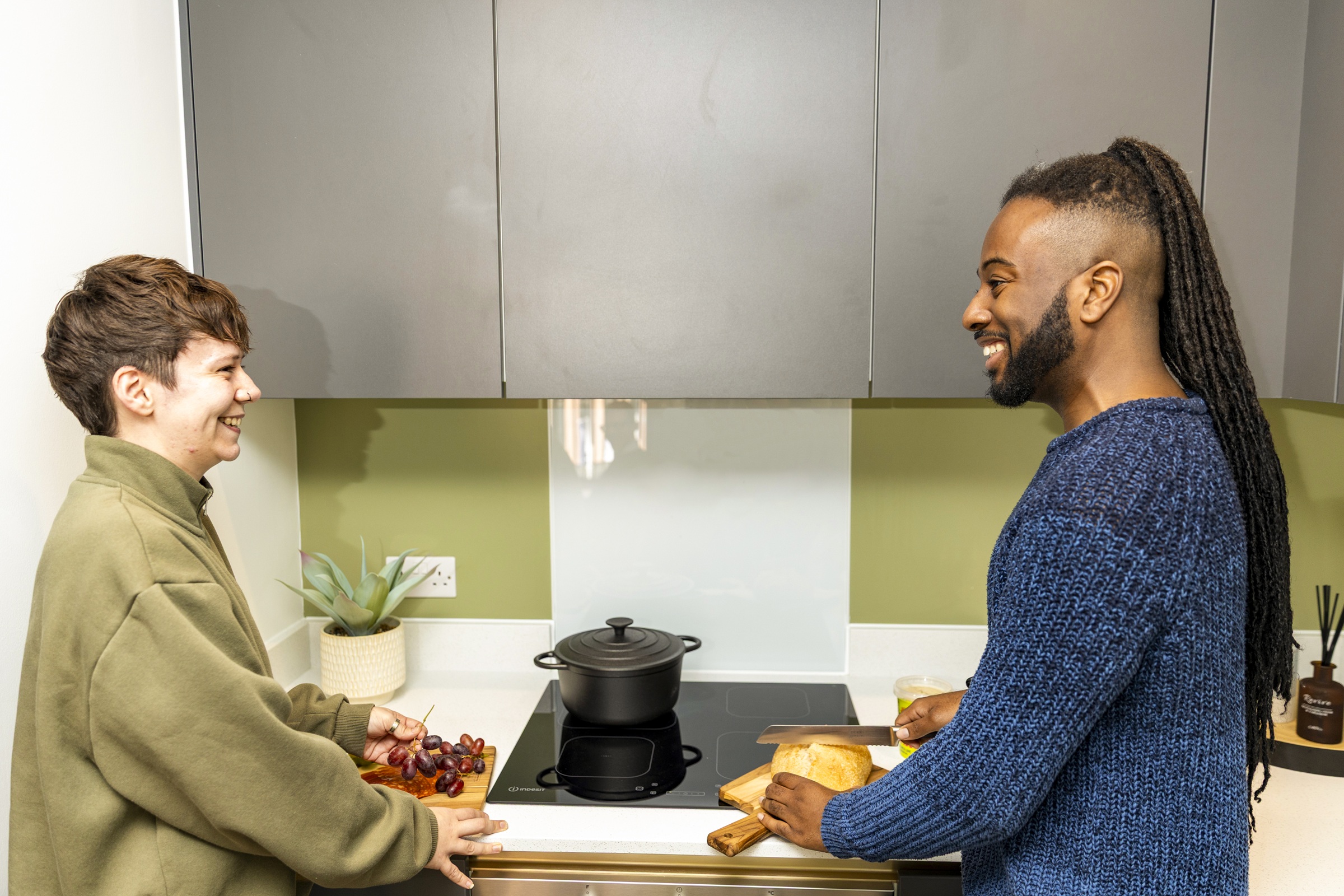A photograph showing two residsents preparing food in their kitchen.