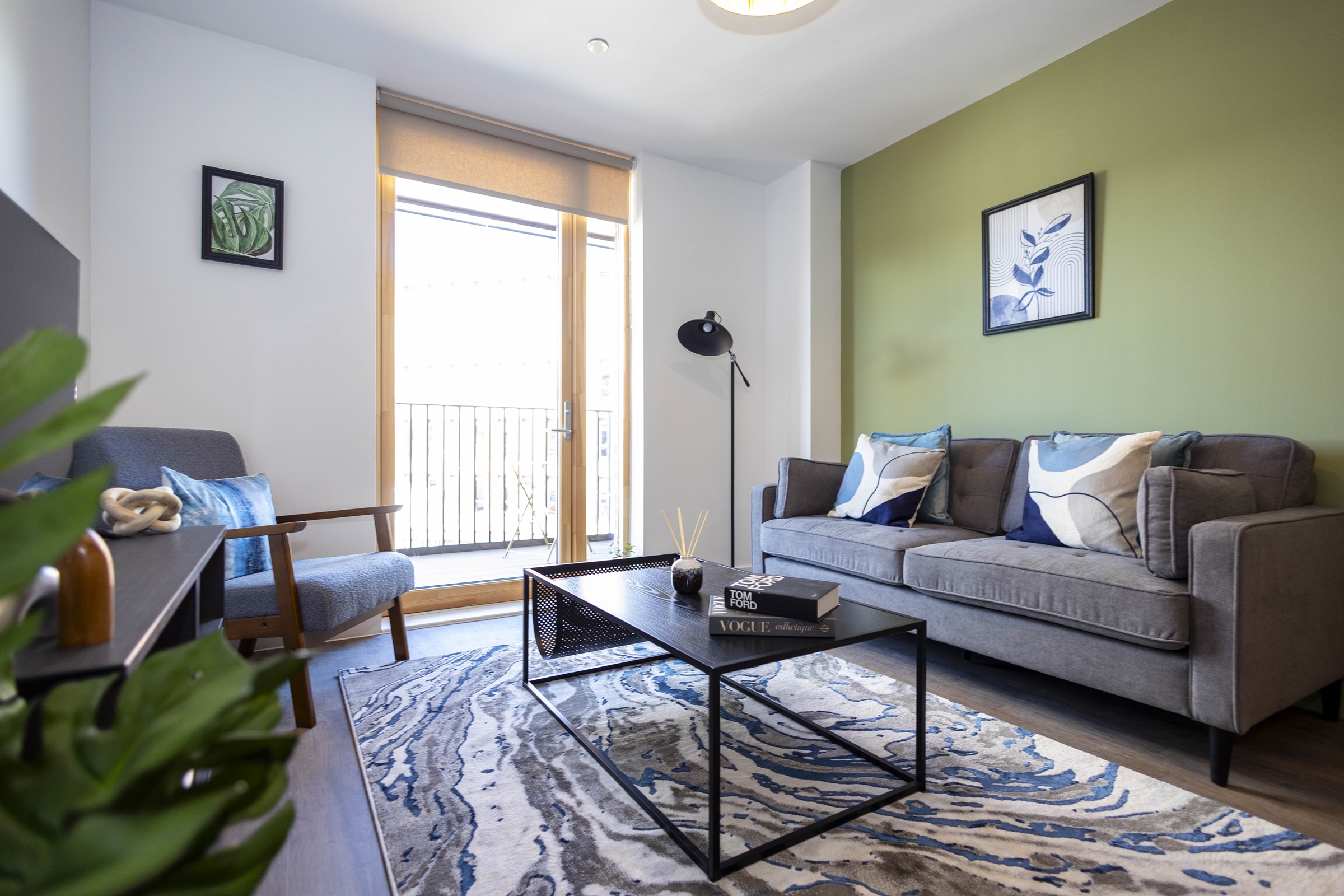A photograph showing a furnished living room, including armchair, sofa, wall art, television and coffee table.