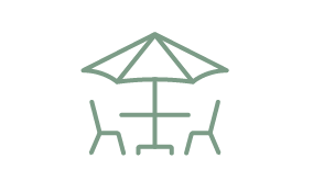 An icon showing two chairs and a table under a parasol umbrella.