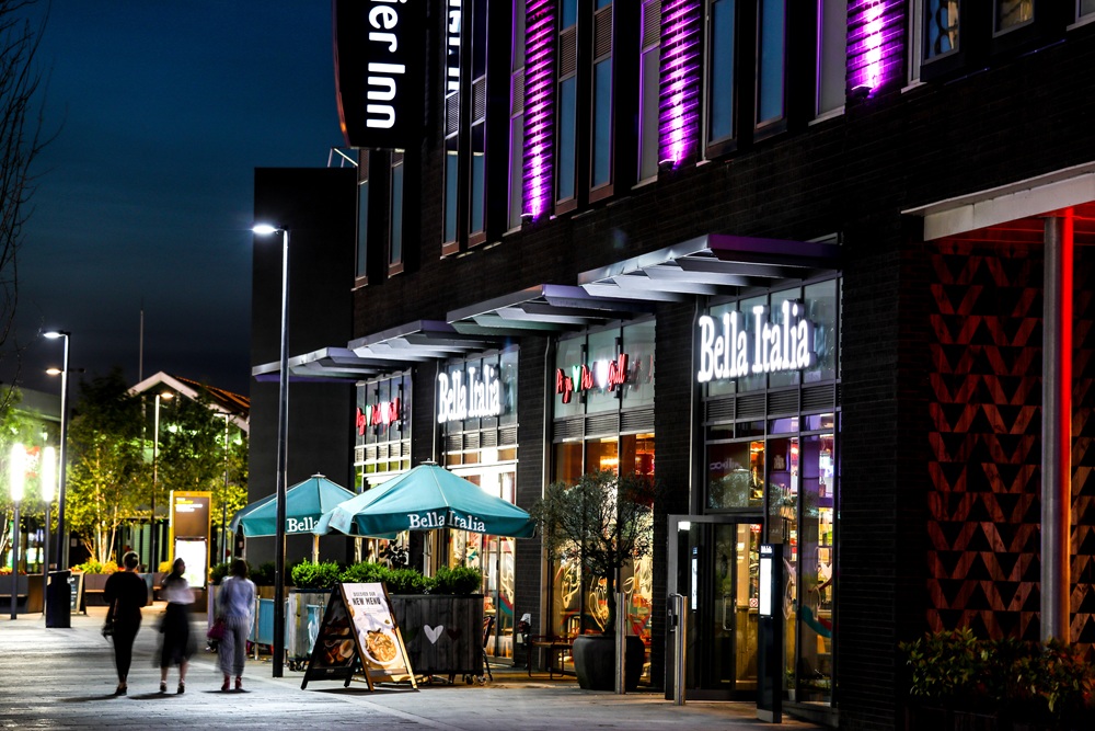 A long exposure photograph showing pedestrians walking outside the restaurants of the Southwater Quarter.
